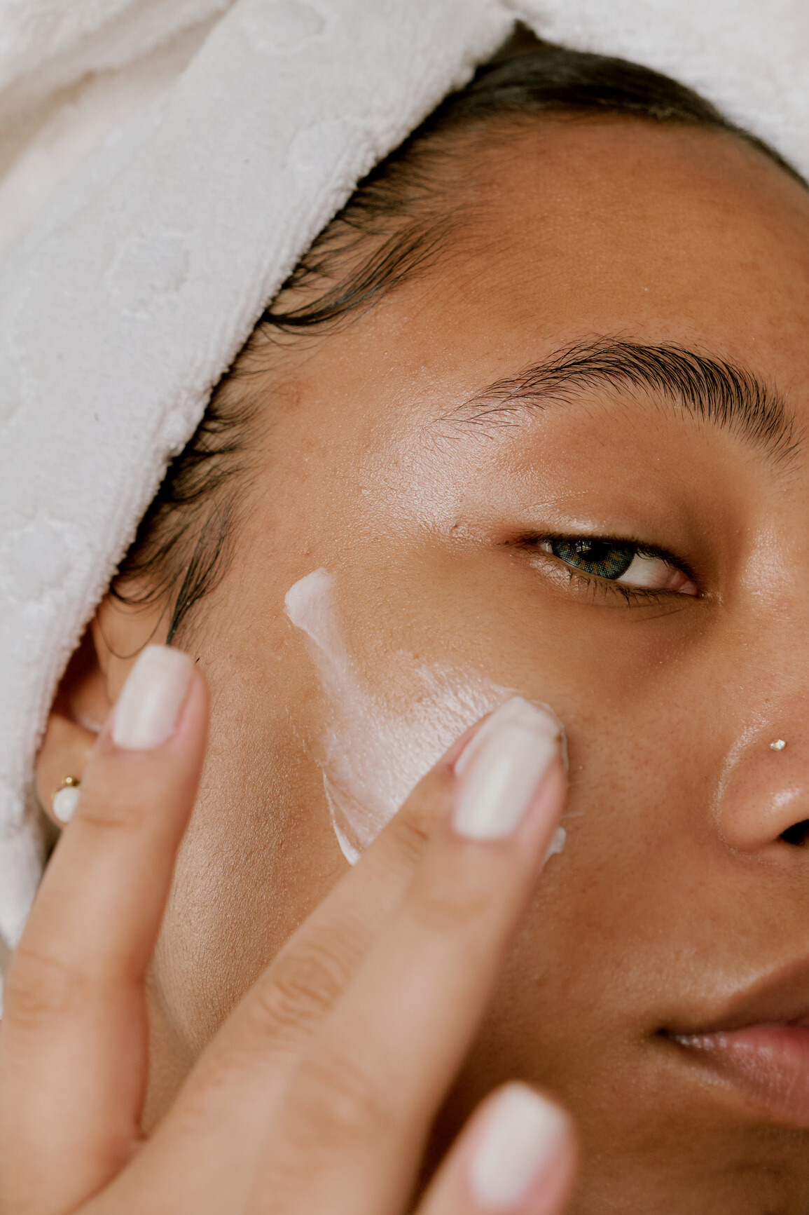 Woman Applying Cosmetic Cream on Face Closeup